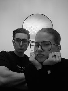 a man and woman are posing for a photo in front of a mirror with their hands on their chins