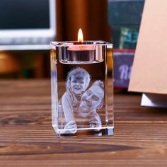 a small glass candle holder with a photo on the front and inside, sitting on a wooden table