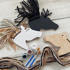 some crafting supplies are laid out on a table with scissors and thread, including wooden horses