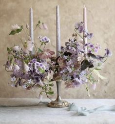 an arrangement of flowers and candles on a table