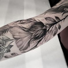 a woman's arm with black and white tattoos on it