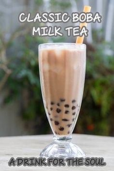 a drink in a tall glass on top of a table with the words, classic boba milk tea