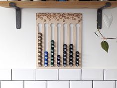 a wooden rack holding several bottles on top of a white tiled wall next to a shelf