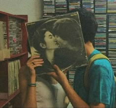 a man holding up a record in front of a woman's face with an album on it