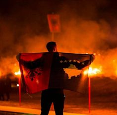 a man holding a flag in front of a fire