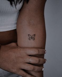 a woman's arm with a small butterfly tattoo on the left side of her arm