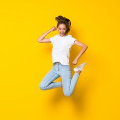 a young woman jumping in the air with her legs spread out and one hand on her head