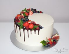 a white cake topped with berries and chocolate drizzle