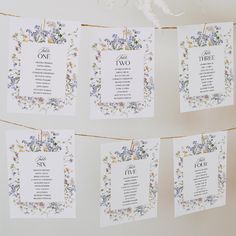 wedding seating cards hanging on a line with flowers