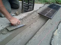 a man is working on cement with a grate