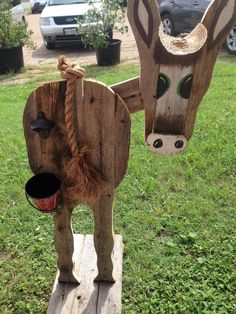 two wooden animals made to look like they are standing on some wood planks in the grass