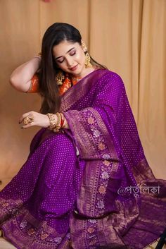 a woman in a purple sari sitting on a chair with her hands behind her head