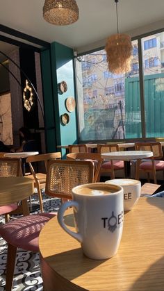 a coffee cup sitting on top of a wooden table in front of a large window