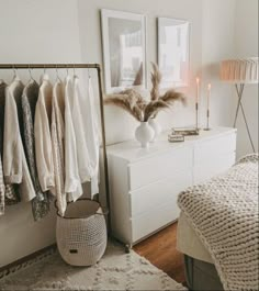 a white bedroom with clothes hanging on the rack