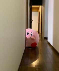 a pink stuffed animal sitting on top of a hard wood floor next to a white wall