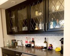 a kitchen with black cabinets and stainless steel counter tops, wine glasses on the cabinet doors