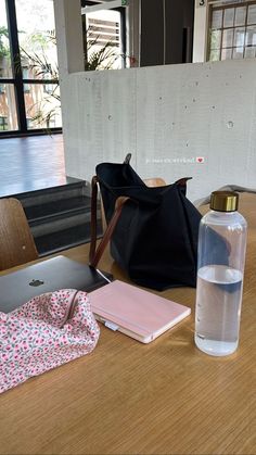 an open laptop computer sitting on top of a wooden table next to a water bottle