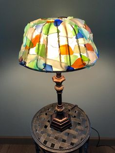 a lamp that is sitting on top of a table next to a light fixture with a multicolored glass shade