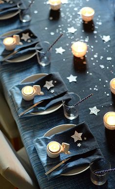 a long table is set with candles and napkins for an outer space themed party