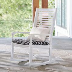 a white rocking chair with a black and white pillow on it's seat cushion