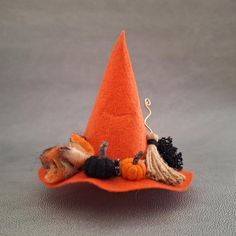 a small orange hat with black and brown decorations on the top, sitting on a gray surface