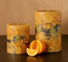 two candles sitting next to each other with orange slices and leaves on the candle holders