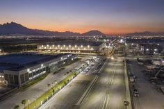 an airport at night with lights on and cars parked in the parking lot near it