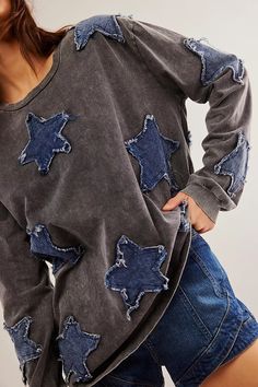 a woman is standing with her back to the camera, wearing a grey sweatshirt with blue stars on it