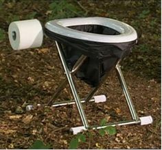 a toilet sitting on top of a metal stand in the dirt next to some trees