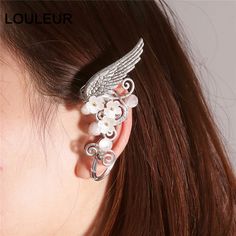 a close up of a person wearing an ear cuff with flowers and wings on it