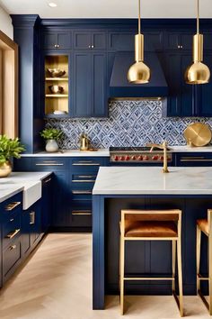 a kitchen with blue cabinets and gold pendant lights hanging from the ceiling over the island