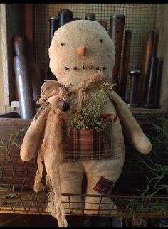 a stuffed snowman sitting on top of a shelf next to a basket filled with plants