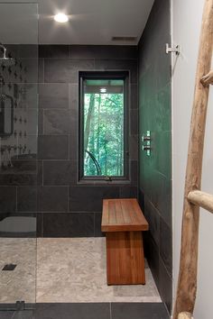 a walk in shower sitting next to a window with a wooden bench on the side