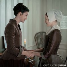 two women standing next to each other in front of a table with candles on it