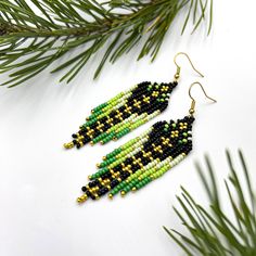 Elevate your style with these enchanting green dangle earrings.  Crafted with precision and a keen eye for design, these black beauties are adorned with intricate seed beads and sparkling crystals.  A perfect gift for women who appreciate unique and handmade accessories. Embrace the artistry of these beaded wonders and make a stylish statement. MATERIALS: Earrings are made of black, gold and 3 shades of green seed beads. Please use the drop down menu to select your preference:  * Stainless steel Earring Inspired, Gold Beaded Earrings, Earring Unique, Fringe Earring, Native Crafts, Jewerly Beads, Beaded Jewlery, Brick Stitch Earrings, Adjustable Bra