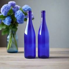 two blue bottles sitting on top of a table next to a vase filled with flowers