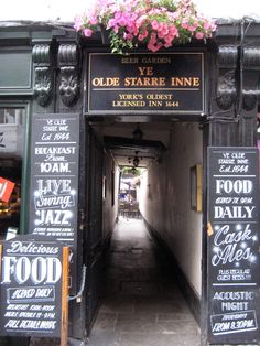 the entrance to an old - fashioned restaurant with chalkboard menus and flowers hanging above it