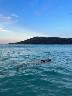 a person floating in the water with their head above the water's surface and an island in the distance