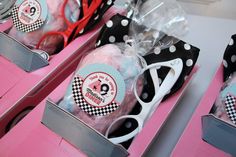 some scissors are sitting in a box on a pink tablecloth with black and white polka dots