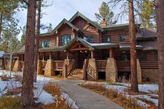 a large log home surrounded by trees and snow