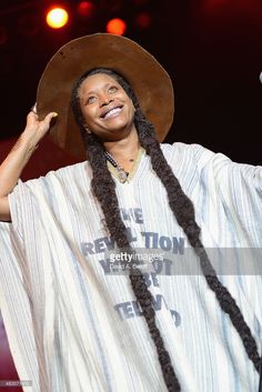 a woman with long braids and a hat on her head is smiling at the camera