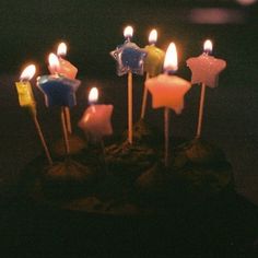 a birthday cake with lit candles in the shape of stars