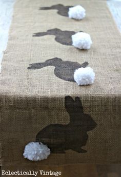 the table runner is decorated with silhouettes of rabbits and pom - poms