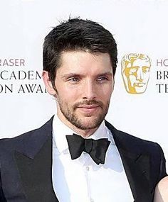 a man in a tuxedo standing next to a woman