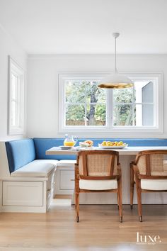 two chairs and a table with food on it in front of a window, next to a bench