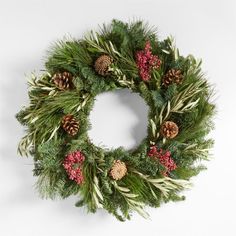 a christmas wreath with pine cones, berries and greenery is displayed on a white background