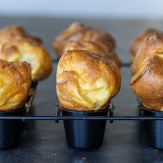 several muffins sitting in black plastic cups on a rack