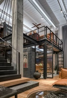 an industrial loft with exposed ceilings and wood flooring is featured in this image, there are two couches on either side of the staircase