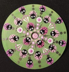 a green plate with pink and black ladybugs painted on the side, sitting on a table