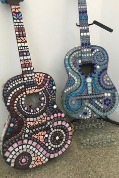 two guitars made out of mosaic tiles are sitting next to each other